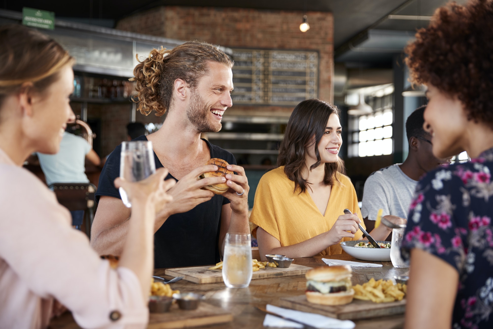 Group Of Young Friends Meeting For Drinks And Food In Restaurant
